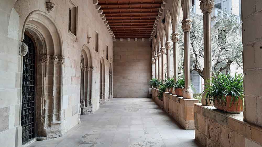 Best Montserrat Tour from Barcelona (With Tapas + Winery Visit) 1 If you're planning a Montserrat tour from Barcelona, arrive early so you can get photos witout anyone in them like this view of the clister next to the Monastery entrance, with columned archeways, and decoratvie carvings over the doors.