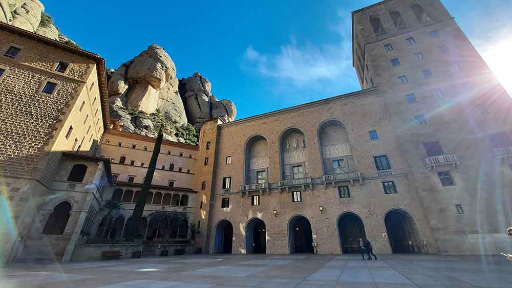 Best Montserrat Tour from Barcelona (With Tapas + Winery Visit) 6 Early morning sunbeam shining past the monastery of Montserrat. The place is deserted - only two people are here with us early in the day.