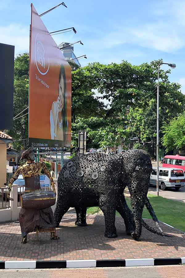 Roadside scrap metal elephant sculpture made from break discs and other car parts. There is a sculpture of a man next to the elephant also in scrap metal. 