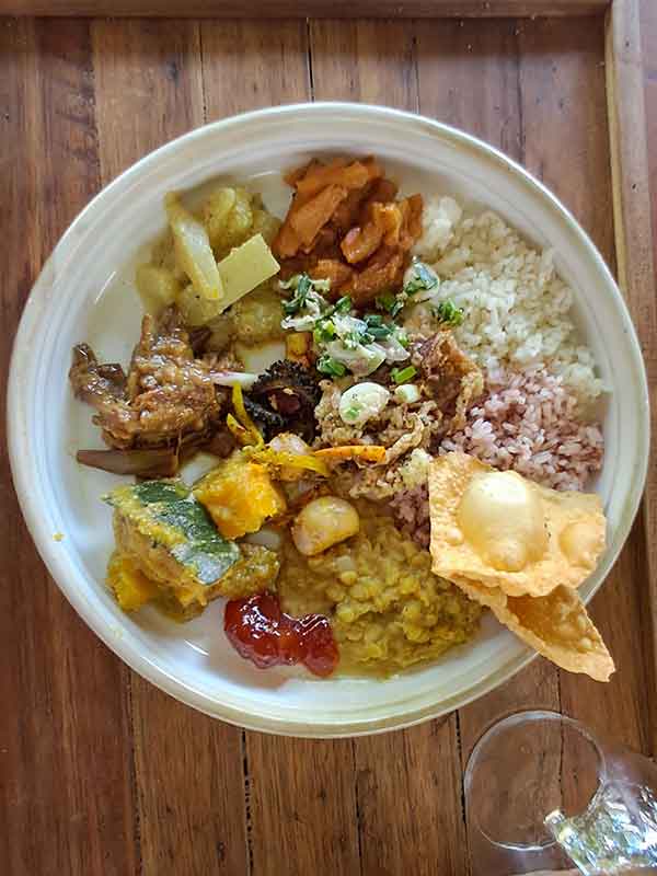 A plate with various traditional food. There is a mix of curries, dahl, chutneys, vegetables, rice and popadoms.