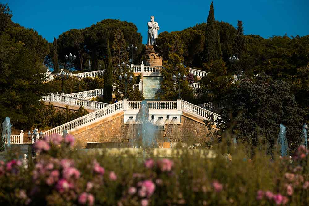 The big park of Parque Grande José Antonio Labordeta with a series of steps leading up through trees with a statue at the top. 
