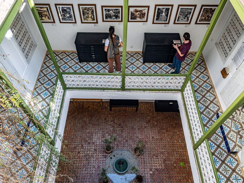 A view down into the courtyard of the Maison de la Photographie, showcasing the different levels with a variety of framed and displayed photographs, observed by visitors.
