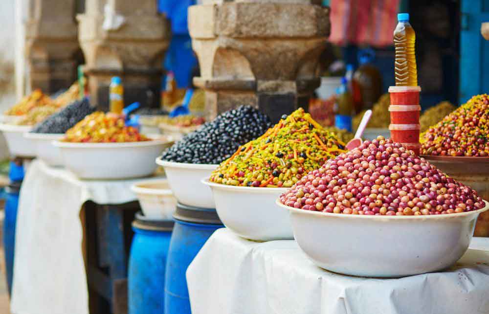 Bowls of olives with bottles of olive oil at a market in Morocco.