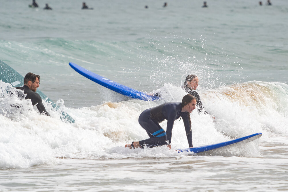A group of surfers catching waves near the shore, capturing the thriving surf culture that helps explain what San Sebastian is known for among adventure lovers.