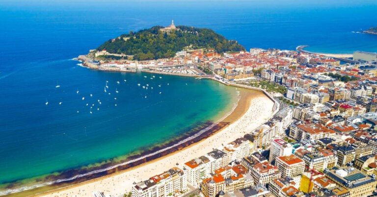 An aerial view of San Sebastian’s La Concha Bay with boats dotting the water and the city hugging the shoreline, offering a quintessential image of what is San Sebastian known for.