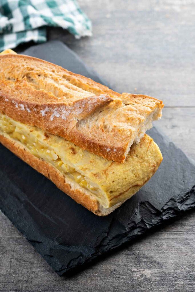 A Spanish omelet sandwich with thick slices of potato tortilla tucked into a crusty baguette. A popular vegetarian choice for breakfast or lunch in Spain.
