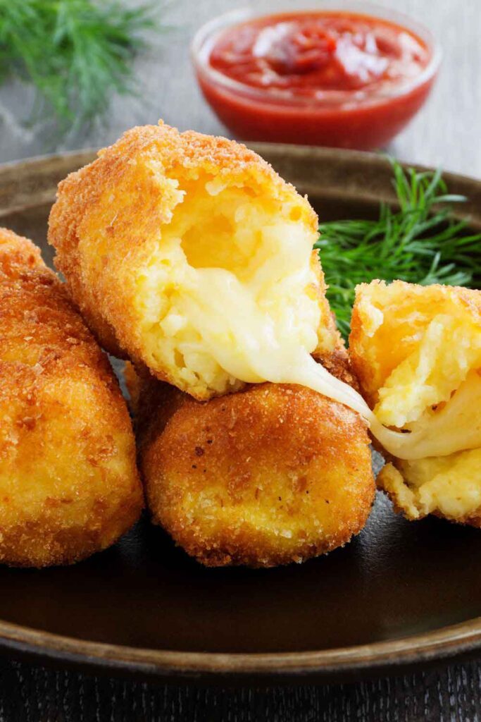 Golden croquettes with melted cheese filling, served with tomato dipping sauce and fresh dill. A creamy indulgence that’s part of the vegetarian tapas scene in Spain.