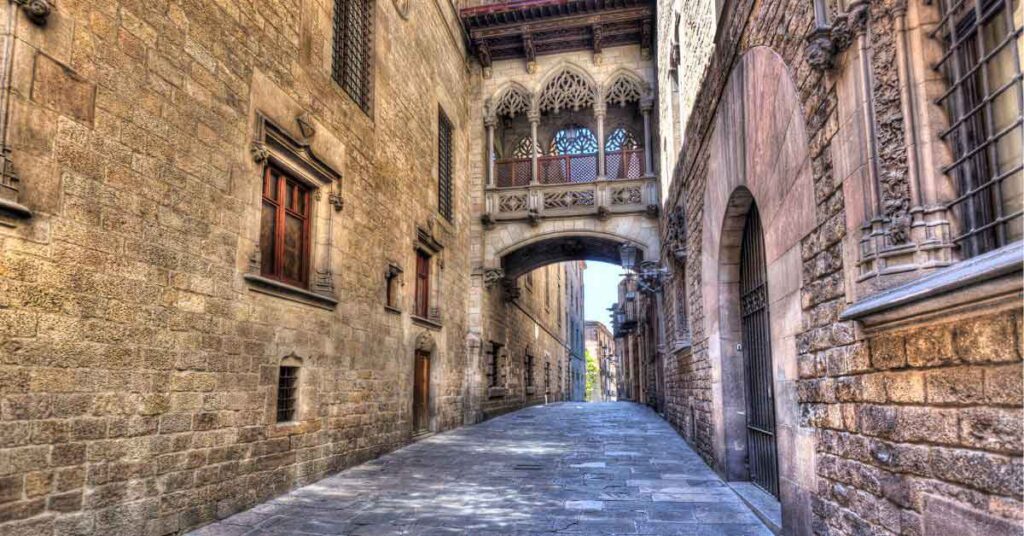 Gothic Quarter, Barcelona Stone-paved alley in Barcelona’s Gothic Quarter, featuring the iconic Bishop’s Bridge—showcasing the historic charm of one of the best cities to visit in Spain.