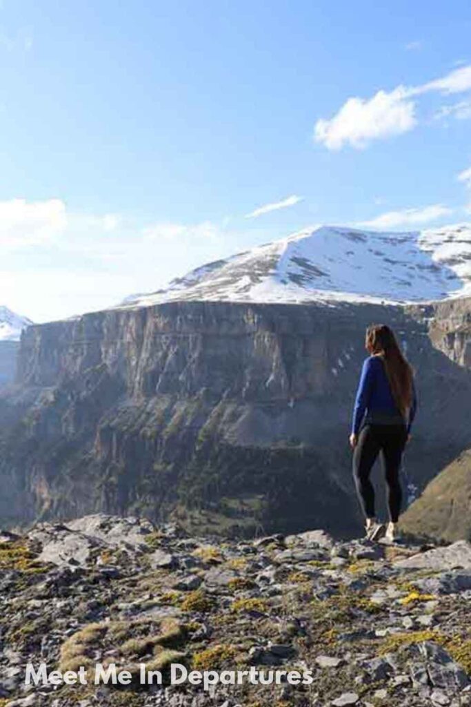 Ordesa y Monte Perdido NP, Aragon Region Woman (me) standing on a rocky cliff edge overlooking the snow-capped peaks and dramatic cliffs of Ordesa National Park in the Spanish Pyrenees. A breathtaking landscape that highlights the wild, mountainous side of northern Spain.