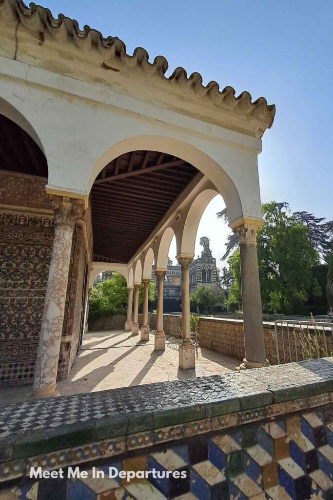 Pabellón de Carlos V at the Real Alcázar of Seville, with arched colonnades, patterned tiles, and morning sunlight casting shadows, photographed during early access before the palace grounds filled with visitors.