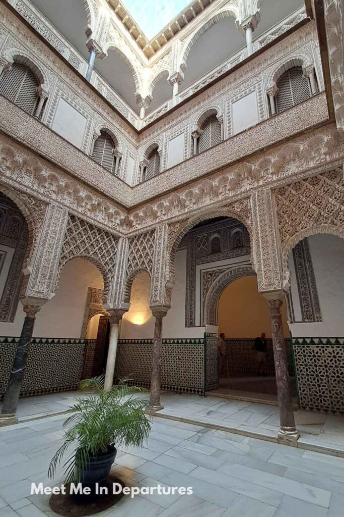 Patio de las Muñecas at the Real Alcázar of Seville, with delicate stucco arches, marble columns, and patterned tilework, photographed during early morning access before other visitors arrived.
