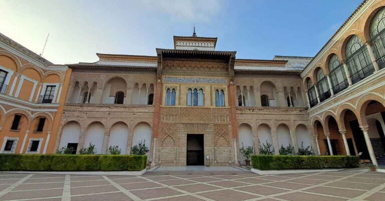Courtyard view of the stunning Mudejar-style Palacio de Pedro I at the Royal Alcázar of Seville, featured in the Alone in the Alcazar Tour review by Walks Tours in Seville, showcasing the intricate architecture and peaceful atmosphere of an early morning visit.