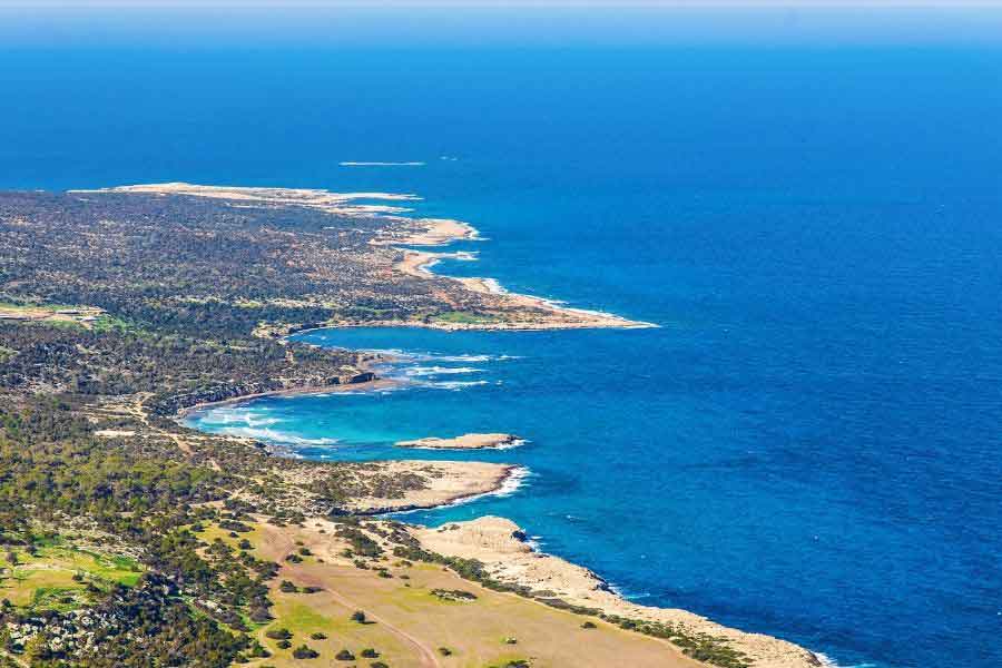 Akamas Peninsula, Cyprus Aerial view of the Akamas Peninsula in Cyprus, with rugged headlands jutting into the vivid blue Mediterranean Sea. The coastline is fringed by pine forest, rocky coves, and small sandy beaches—an ideal escape for those craving unspoilt nature and gentle winter sunshine in Europe.