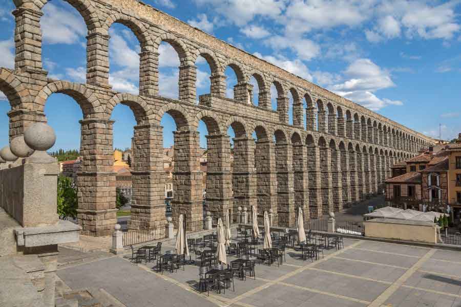 The iconic Roman aqueduct of Segovia, Spain, with tall arches running through the historic city center.