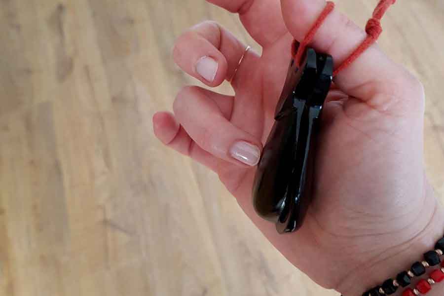 A person holding a pair of black flamenco castanets tied with a red cord — a symbolic and rhythmic souvenir from Spain, perfect for music and dance lovers.