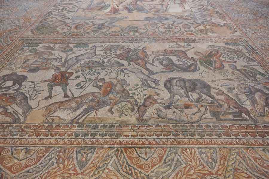 La Olmeda’s, Mosaic Intricate Roman mosaic depicting hunting scenes with animals and hunters, showcasing colorful craftsmanship and detailed artistry.