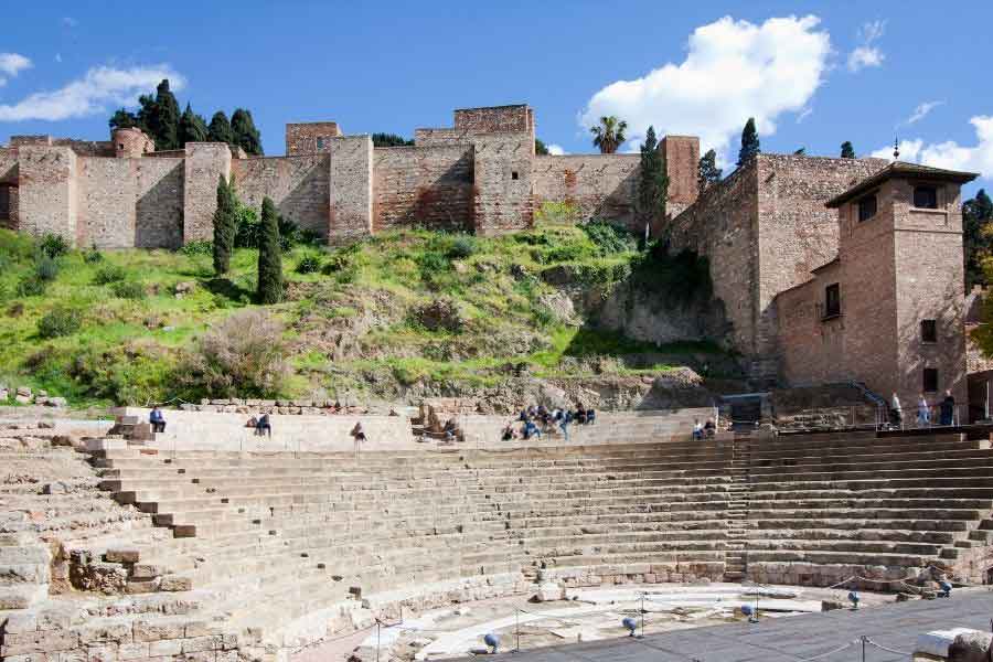 Roman Theatre, Málaga The Roman theatre of Málaga, Spain, located at the foot of the Alcazaba fortress, with stone seating and tourists exploring.