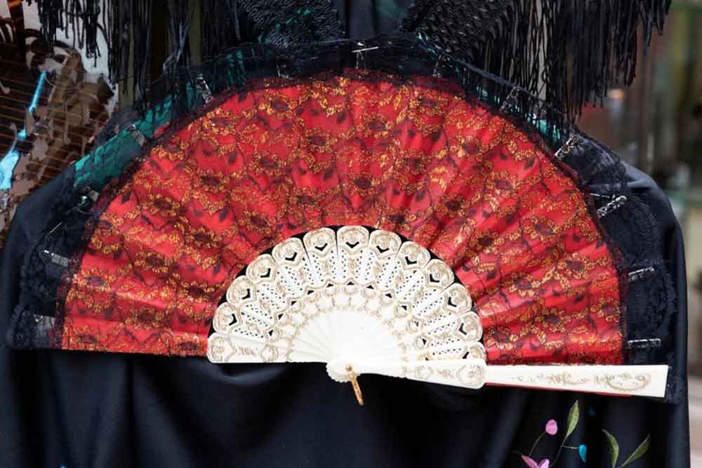A decorative Spanish hand fan with red lace and intricate detailing, often used in flamenco — a beautiful and traditional Spanish souvenir to take home.