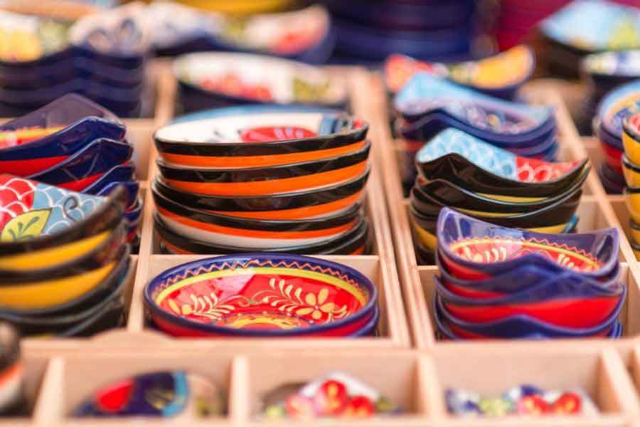 A display of colourful, hand-painted ceramic dishes and tapas plates in a market stall — a popular choice of traditional Spanish souvenirs to bring home.