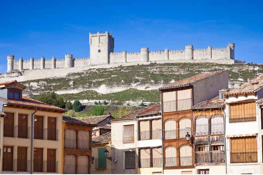 Peñafiel Castle stretching along a hilltop above traditional Spanish houses, a medieval fortress in the Ribera del Duero wine region of Castilla y León.