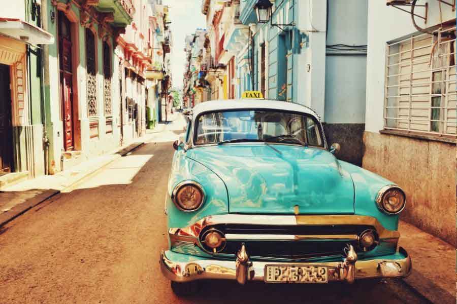 Vintage turquoise taxi parked on a colourful street in Havana, Cuba, one of the most vibrant dream travel destinations for culture and photography lovers.