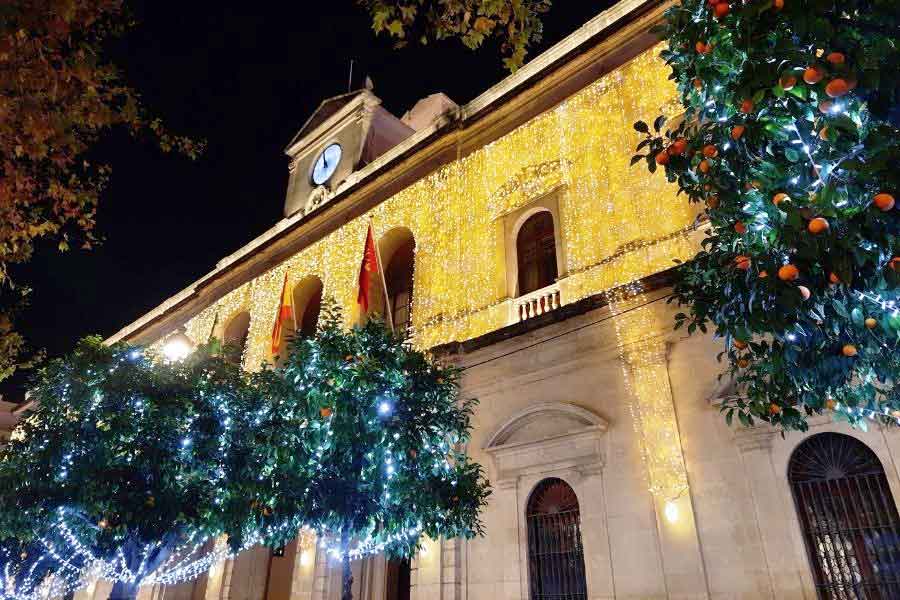 Seville Town Hall at Christmas Seville Town Hall illuminated with golden Christmas lights and orange trees decorated with twinkling fairy lights, creating a festive glow in the heart of the city.