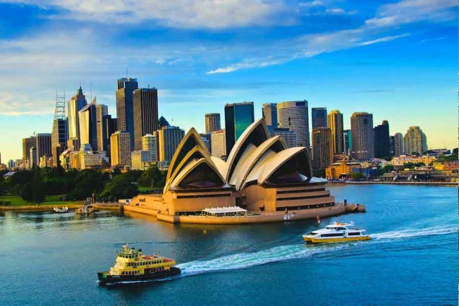 Sydney Opera House and city skyline viewed from the harbour with ferries passing by, one of Australia’s most iconic dream travel destinations.