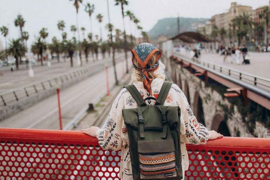 Traveller wearing a patterned shirt, scarf, and backpack while exploring Barcelona’s waterfront in mild winter weather, illustrating light layers perfect for Spain’s coastal cities in winter.