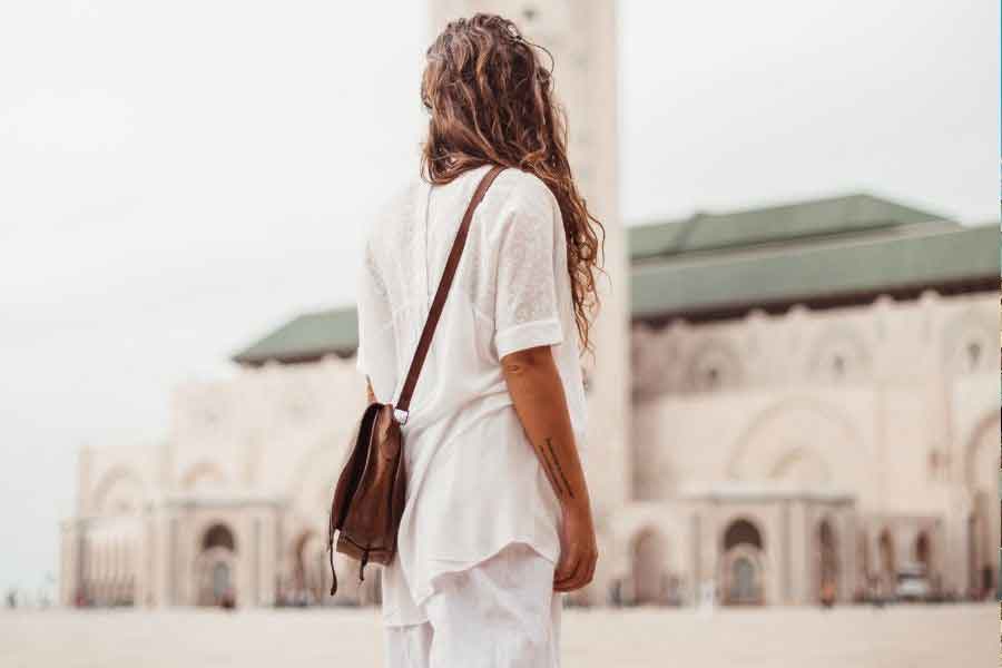 A woman wearing loose modest layers and a crossbody bag while sightseeing in Morocco, offering an outfit example for what to wear in Morocco in winter and practical ideas for dressing comfortably in Morocco’s winter season.