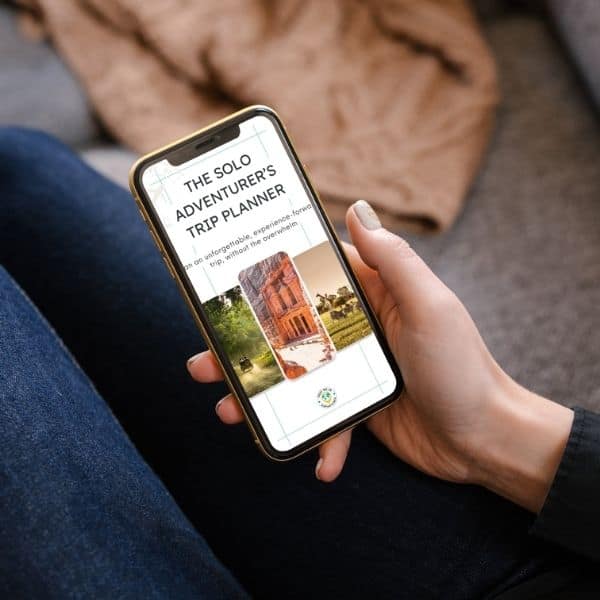 Solo Adventurer’s Trip Planner displayed on a phone screen, held in one hand while sitting on a sofa.