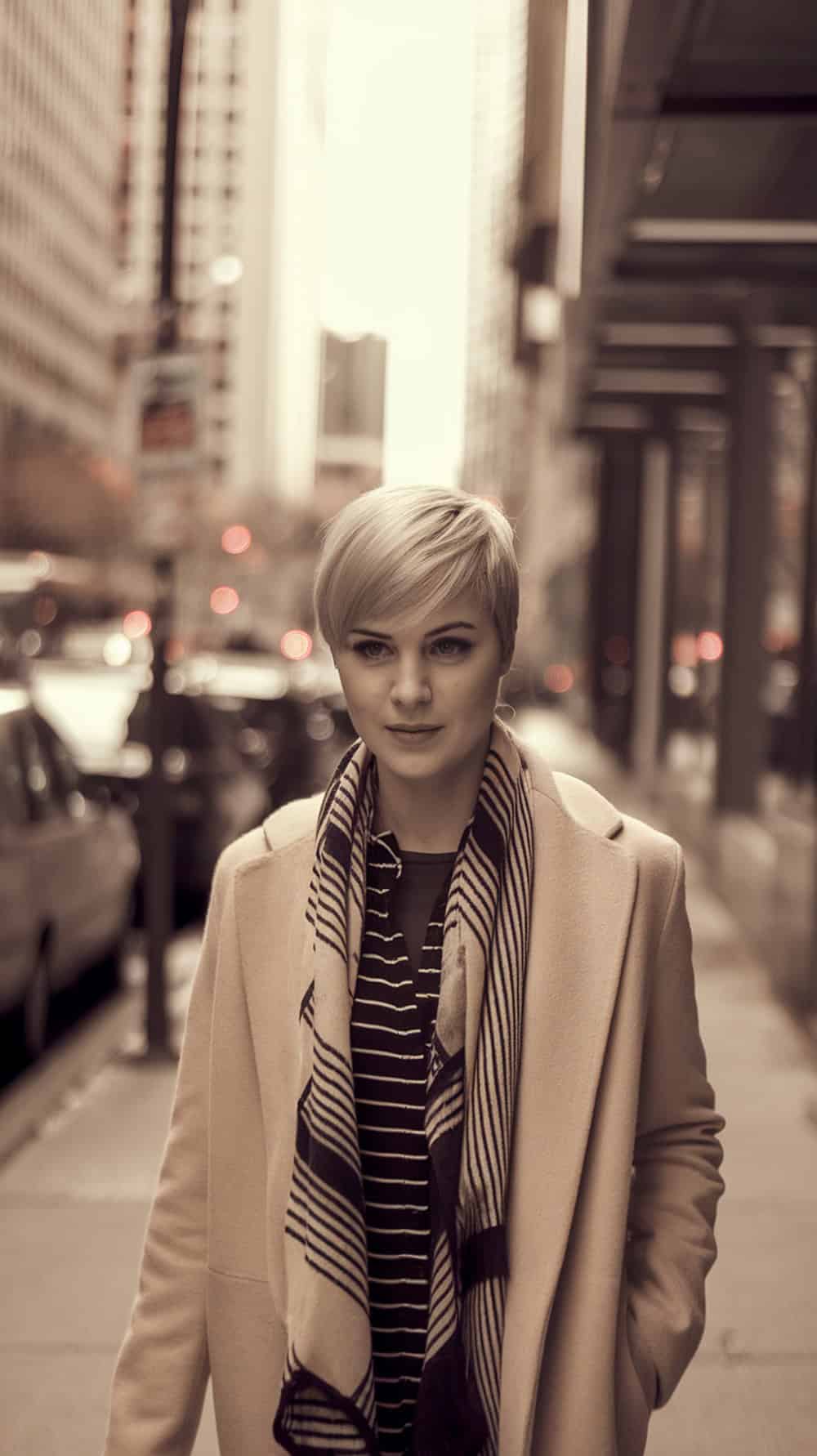 A woman with an asymmetrical pixie haircut walking in a city