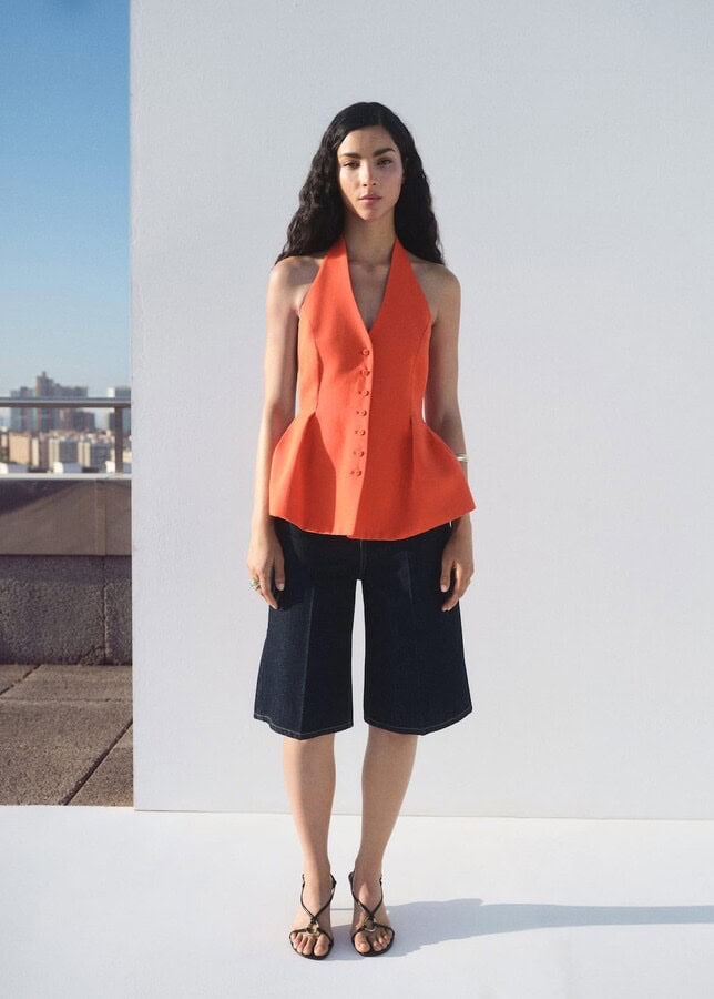 A tailored orange halter-neck vest with structured bodice and peplum waist.
