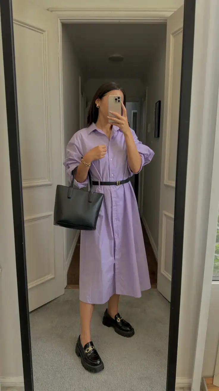 iPhone mirror selfie of a woman in a lilac shirt dress with black chunky loafers, structured tote and slim belt, face not visible, side angle in hallway mirror, indoor natural light, iPhone photo quality