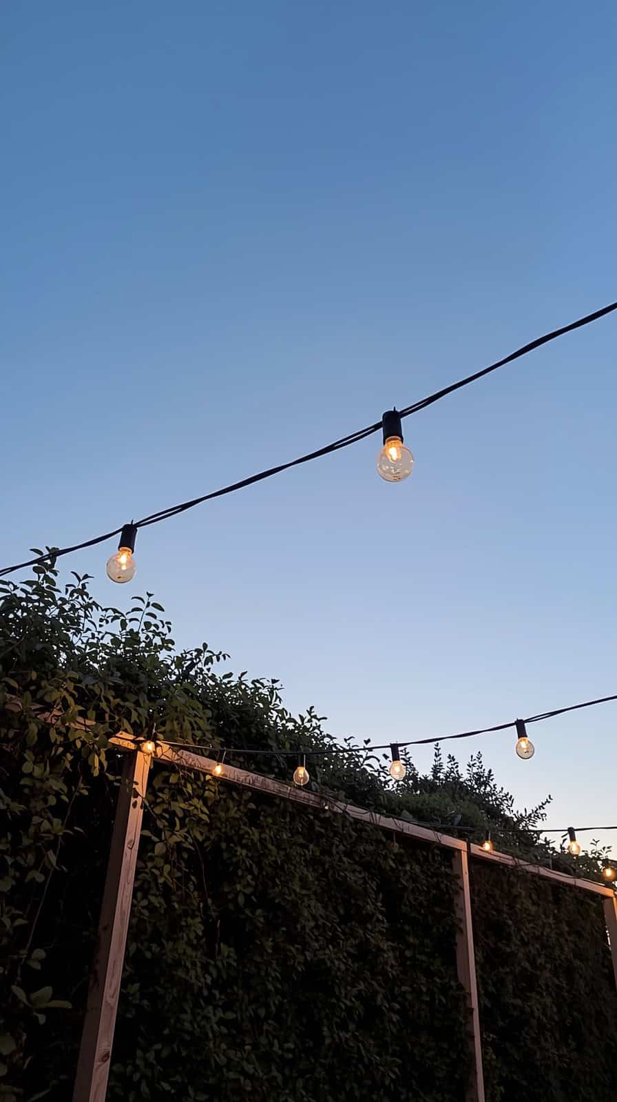 minimalist patio string lights draped overhead in gentle curve creating airy ambiance