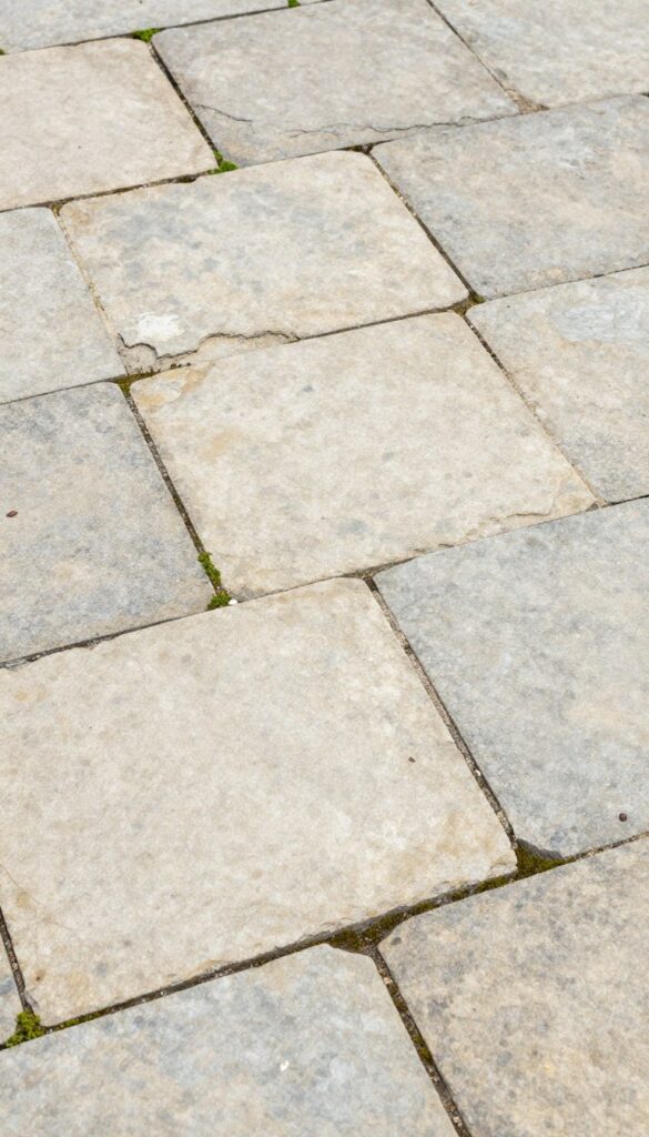 Irregular weathered stone patio flooring with moss growing between joints in authentic English country garden style Irregular weathered stone patio flooring with moss growing between joints in authentic English country garden style