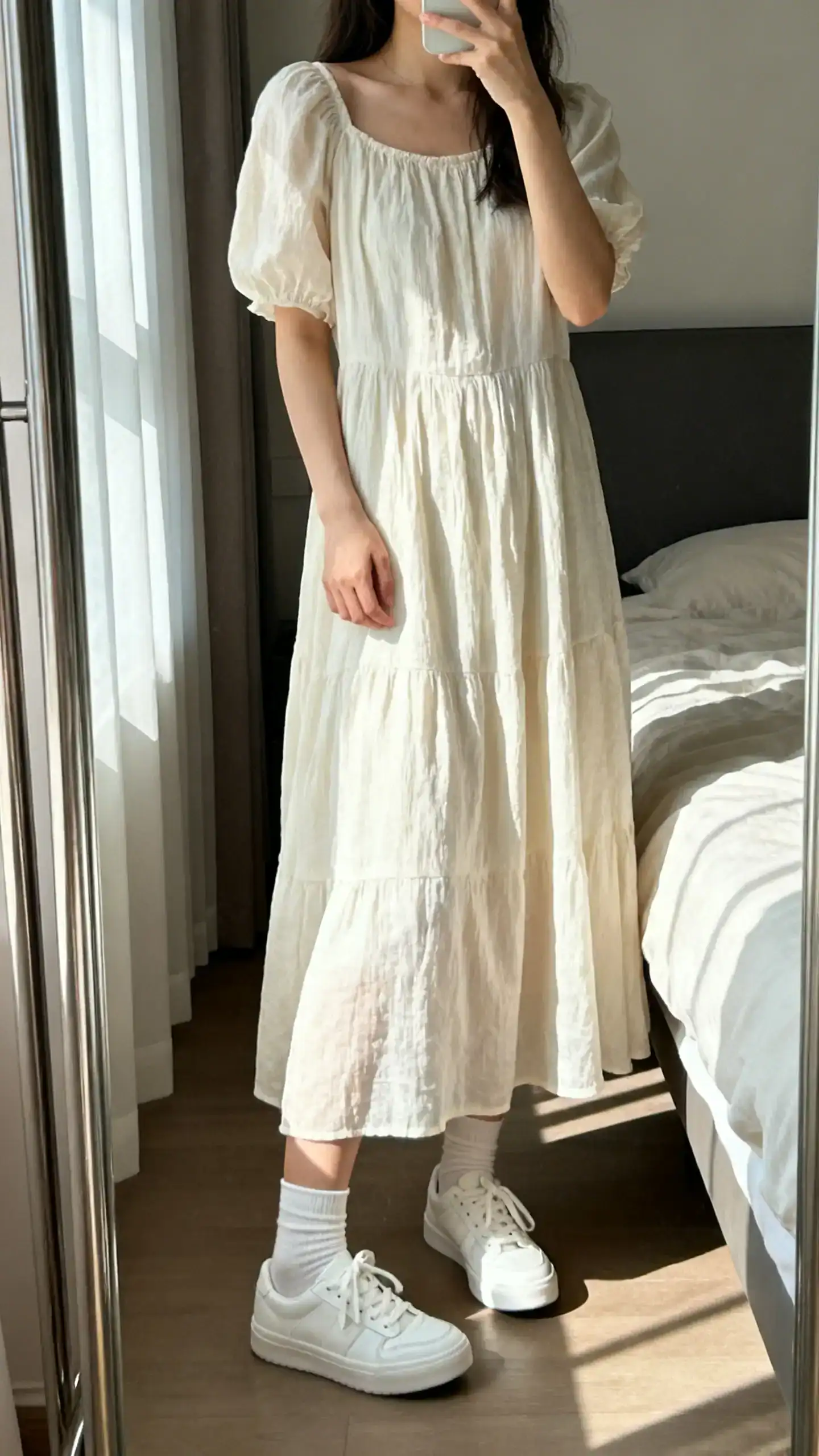 iPhone mirror selfie of a woman wearing a breezy sundress with classic white sneakers and ankle socks, face not visible, cropped at neck, bedroom mirror with morning window light, casual iPhone photo quality