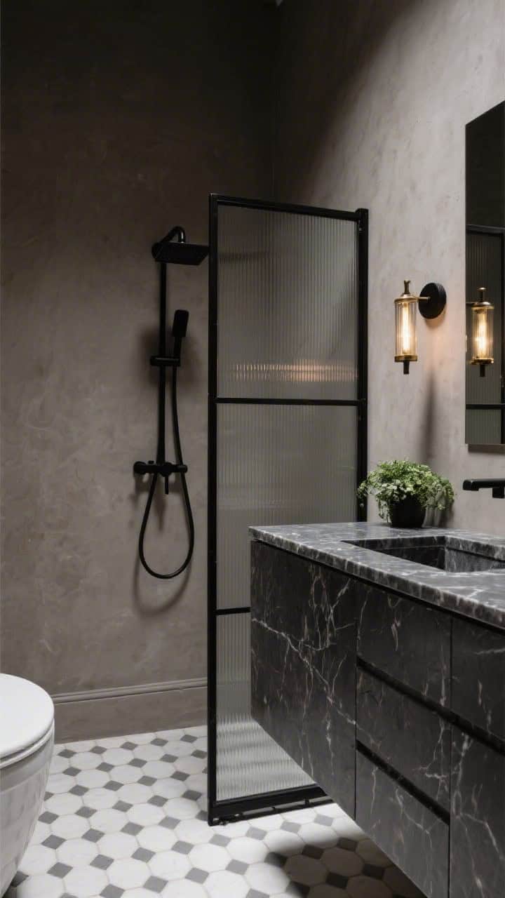 Medium shot of a moody, modern bathroom with warm gray plaster walls and matte black fixtures: slim black faucet, black shower frame, and a Crittall-style glass screen; small Carrara hex tiles underfoot; a charcoal vanity topped in honed marble; flanking sconces in blackened brass cast a soft glow; a hint of greenery on the counter provides contrast; photorealistic, high-contrast noir vibe.