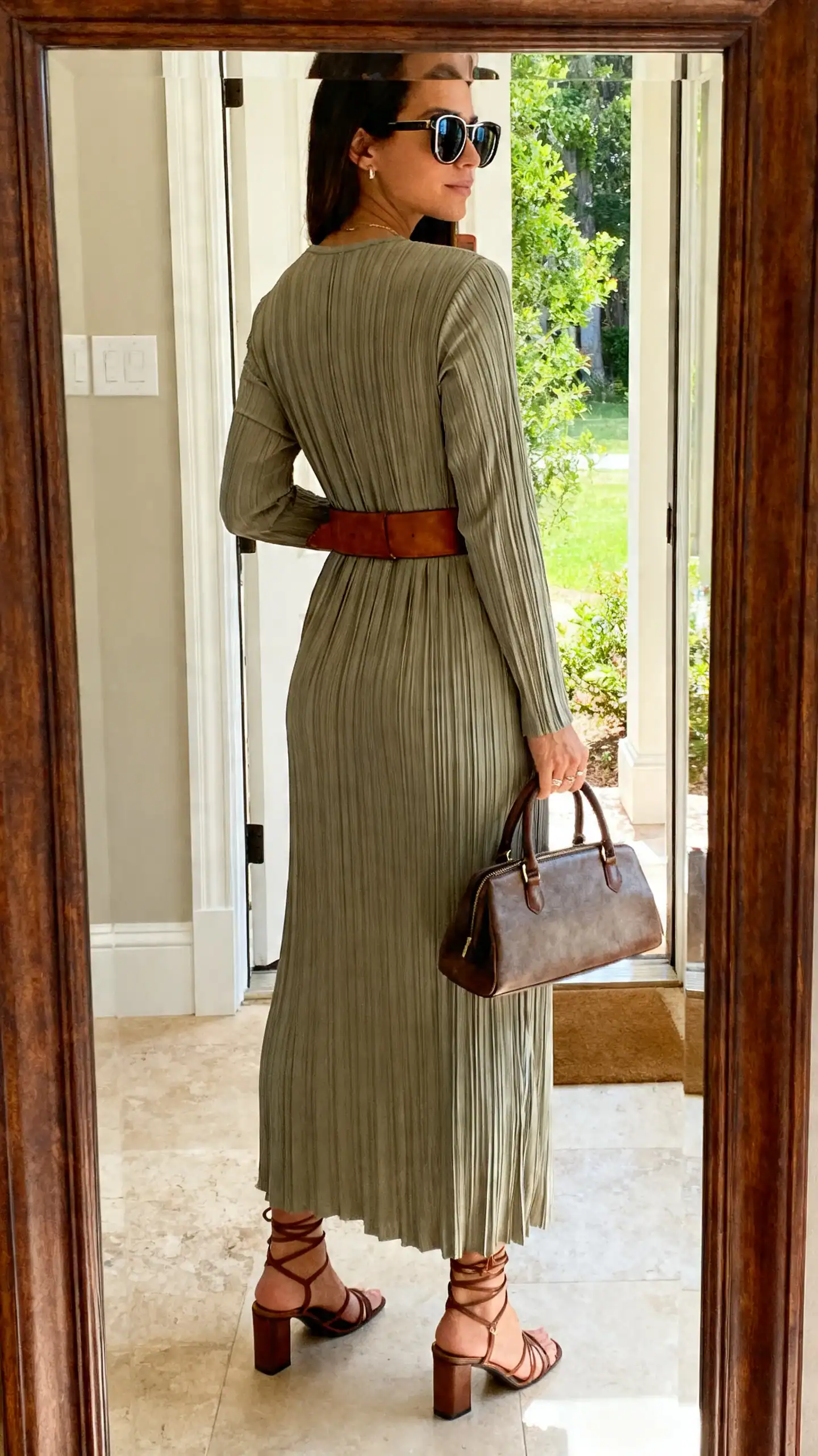 iPhone back-view mirror selfie of a woman in a column maxi dress cinched with a leather belt, strappy heeled sandals, top-handle bag, oversized sunglasses, face not visible, entryway mirror, afternoon natural light, iPhone photo quality