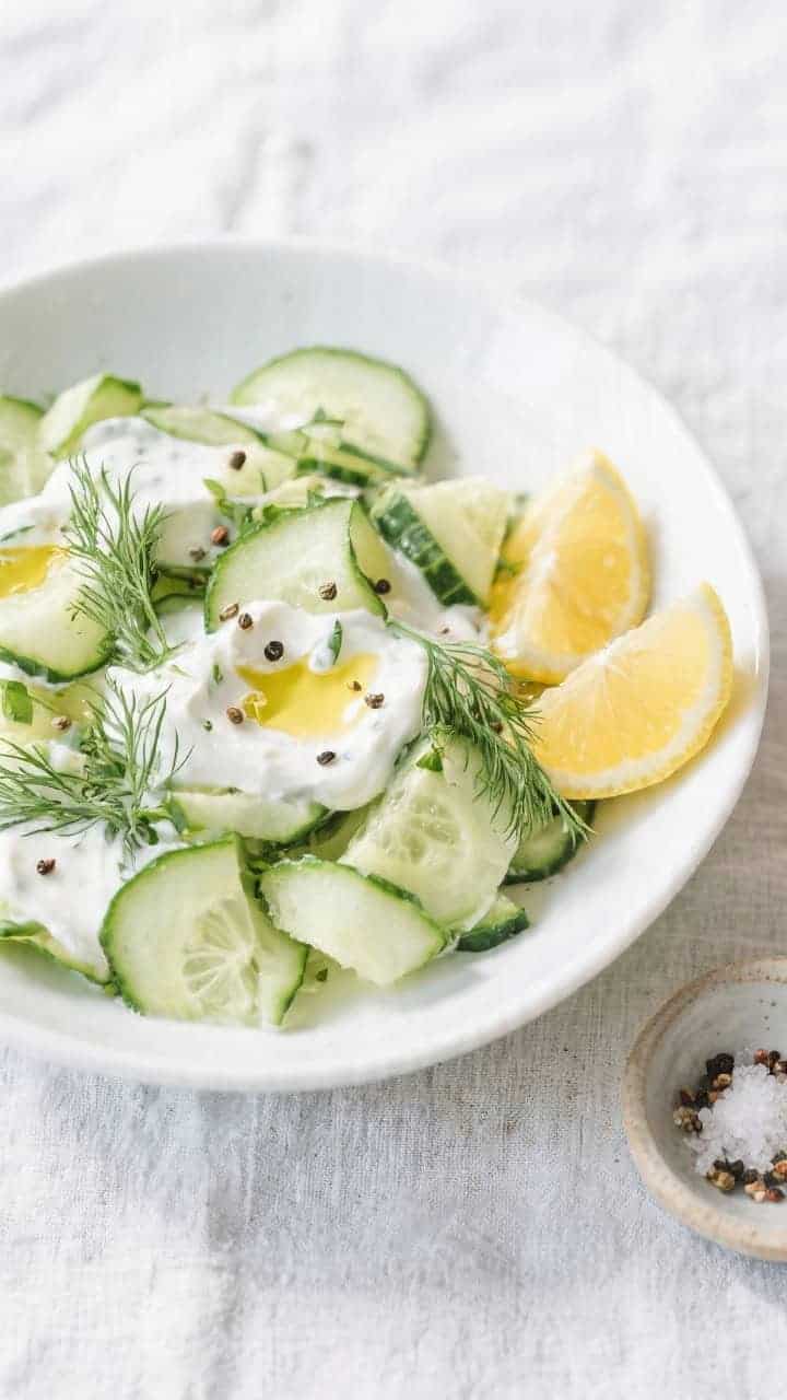 Tasty top view: Overhead shot of the finished cucumber yogurt salad in a wide, shallow white bowl, r