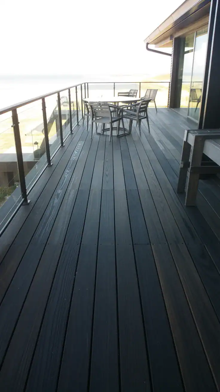 Luxurious blackened oak deck with clear glass railings and contemporary design