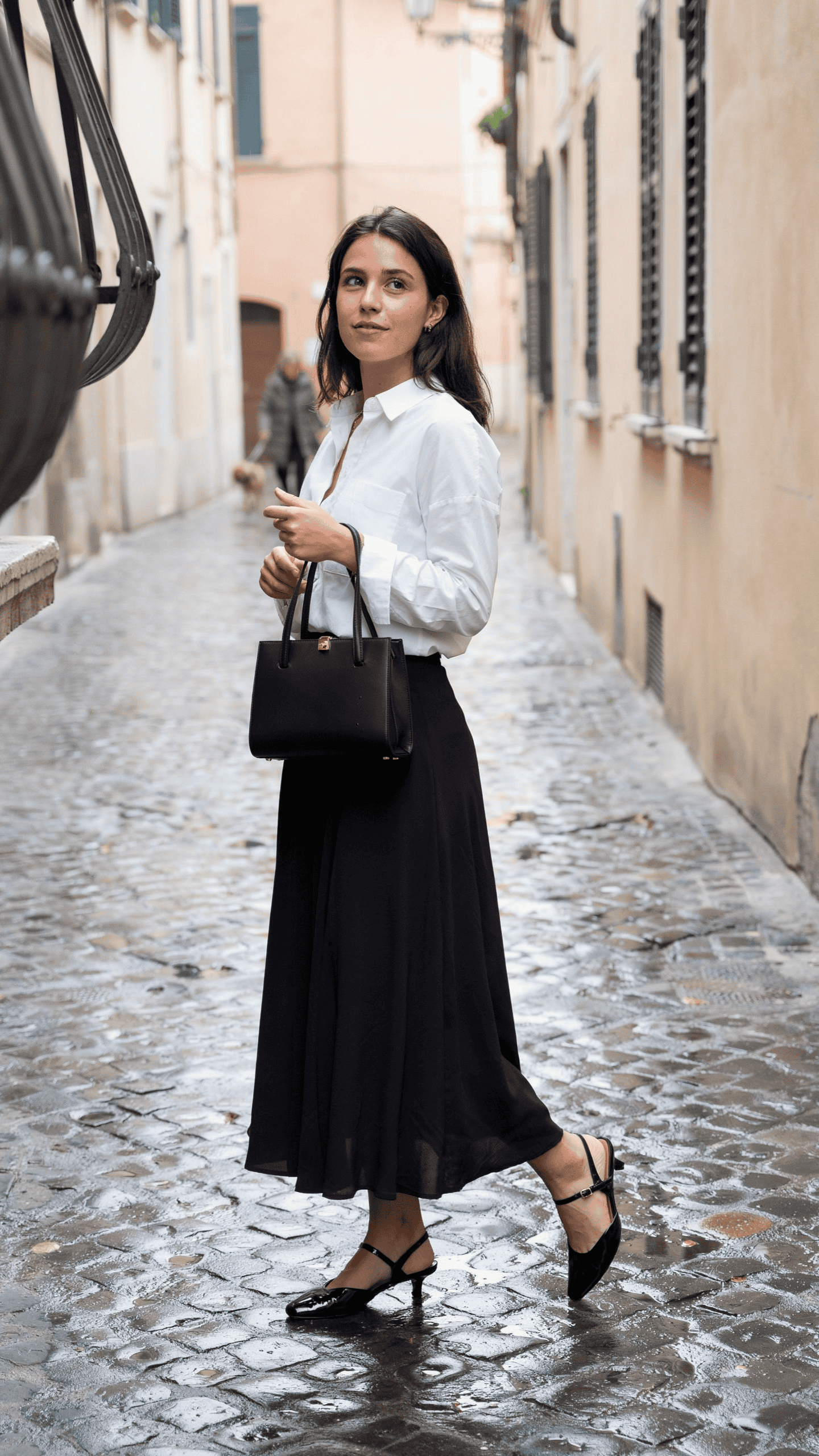 White cotton shirt paired with a flowing black maxi skirt, slingback heels, and a structured handbag.