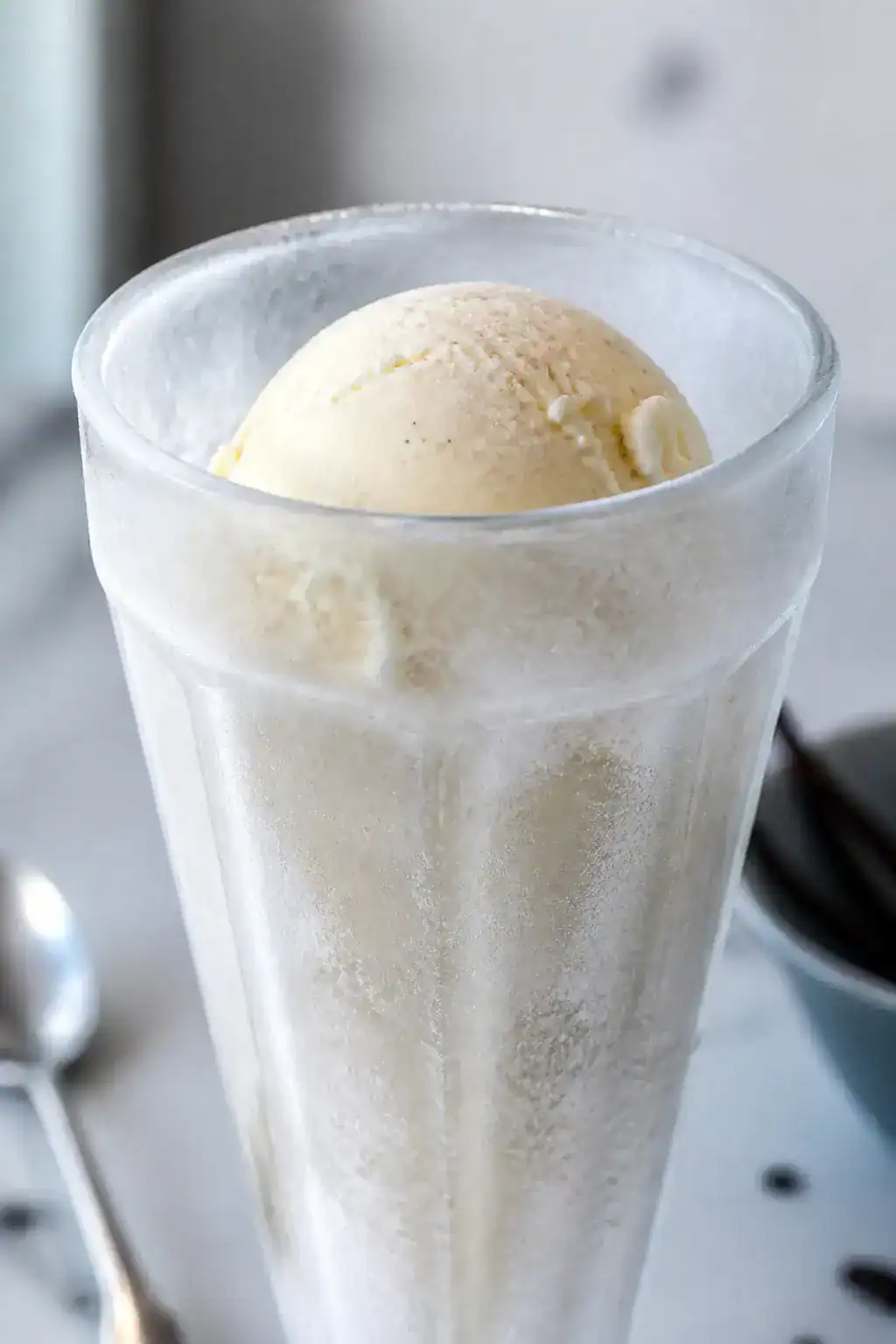 Close-up detail: A frosty tall soda fountain glass just pulled from the freezer with the first softe