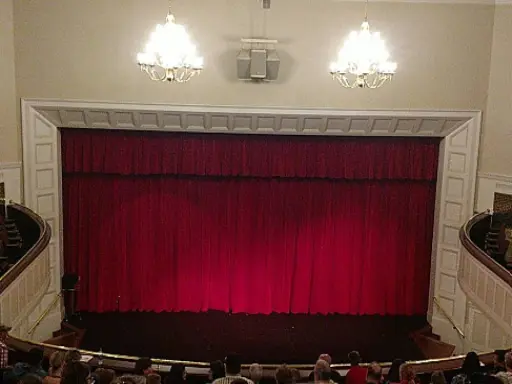 People are waiting for a show to start, talking about their recent Carlisle shower refinishing with Mid State Baths. Alt text: Audience chats about Carlisle shower updates by Mid State Baths before a show starts.