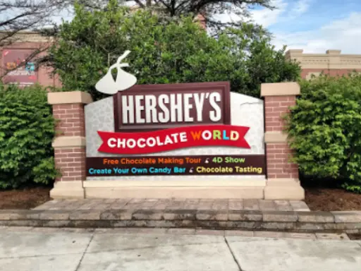 Mid State Baths sign invites families to explore chocolate tours, 4D shows, candy making, and see shower installation options.