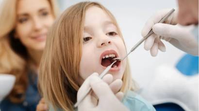 Pediatric dentist gently examining a smiling child’s teeth during a kids dentistry appointment at Mid-Wilshire Dental Care