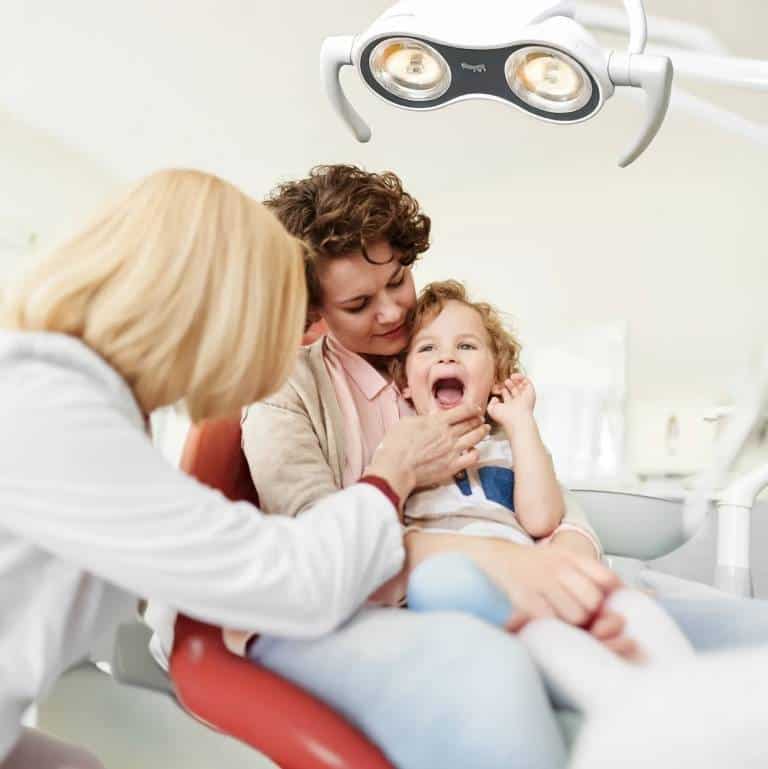 Family dentist at Mid-Wilshire Dental Care treating a smiling child while the parent offers comfort during a friendly dental visit