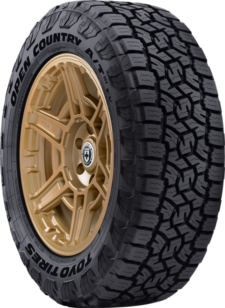 Toyo Open Country A/T III tire with tan alloy wheel for all-weather use.