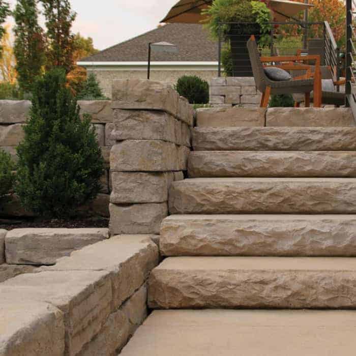 Stone staircase leading to a patio with outdoor furniture and lush greenery.