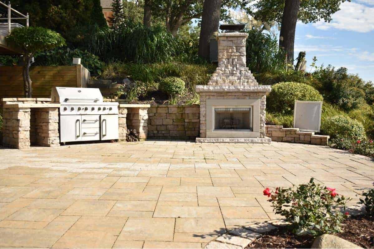 Outdoor kitchen with grill and fireplace for entertaining and cooking.