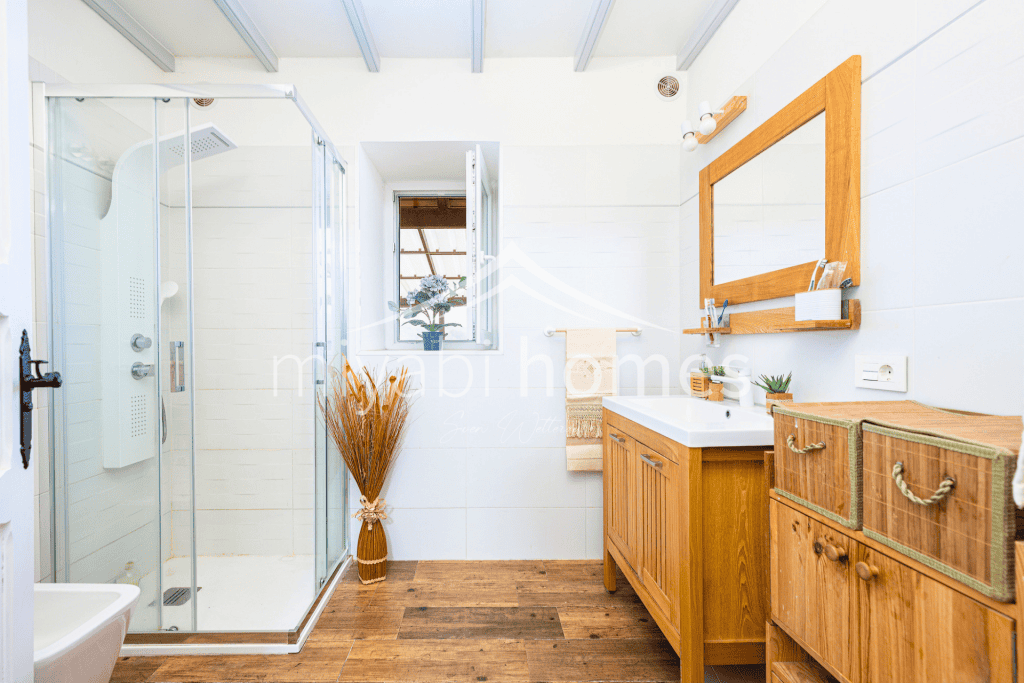 Helles Badezimmer mit Dusche, Holzschränken und Fenster in Gran Canaria.